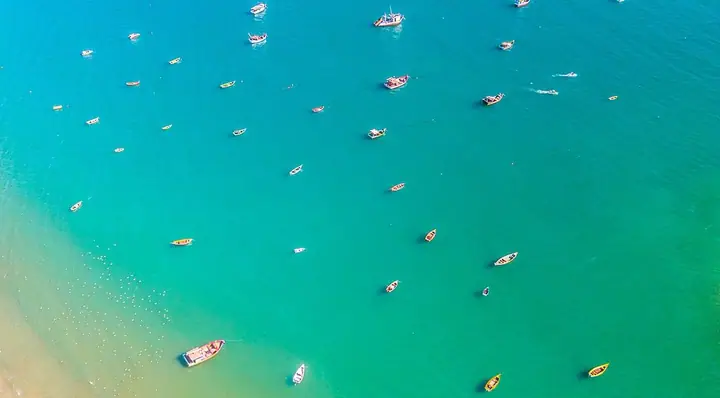 Barcos ancorados em mar verde-esmeralda vistos do alto